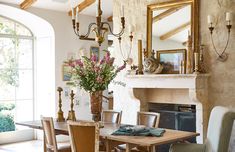 a dining room table and chairs in front of a fire place with a vase of flowers on it