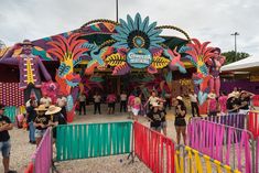 several people are standing in front of a colorful carnival ride at an amusement park or fair