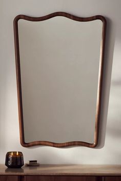 a wooden table topped with a mirror and candle