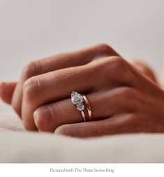 a woman's hand with a diamond ring on her left hand and the other hand holding it