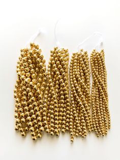 gold beaded beads are lined up on a white surface, with two strings attached to them