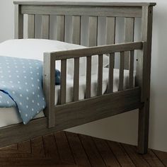 a wooden bed with white sheets and blue polka dots on the pillowcase is shown