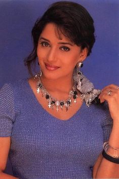 a woman in a blue shirt is posing for the camera with her hand on her shoulder