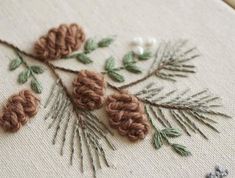 a close up of a cross stitch pattern with pine cones and needles on the embroidery