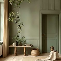 a living room with green walls and wooden furniture, including a plant in the corner