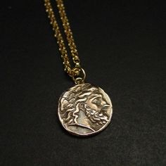 Handmade Zeus pendant by reproducing an ancient Greek coin of Zeus or Jupiter in Latin.The original coin was minted by Philip II (father of Alexander the Great) in Pella, Macedonia between 359 and 336 BC.It represents Zeus, king of the Gods. God of the sky, lightning, thunder, law, order, justice.The quality of Zeus’ particularly elegant portrait on this coin, with a smooth forehead, clean arch of the eyebrow, and finely chiseled nose shows its inspiration by the gold and ivory statue of Zeus by Smooth Forehead, Percy Jackson Necklace, Statue Of Zeus, Elegant Portrait, Lightning Thunder, Ancient Greek Coin, Tarpon Springs, Greek Coins, Roman Coins