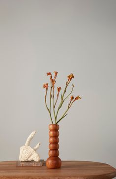 a vase with flowers in it sitting on a table next to a small white shell