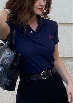 a woman in a blue shirt and black skirt carrying a purse