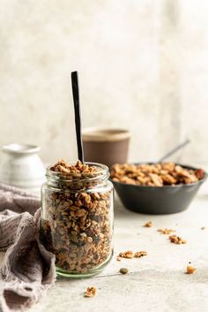 a jar filled with granola sitting on top of a table next to two bowls