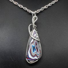 "Fordite Wire Wrapped Jewelry Description:  *Designer Fordite Detroit Agate Cabochon: 40mm x 20mm Triangle Shaped *Pendant Approximate Size: 2 1/2\" long including bail x 1\" at widest point  *Free Rope Chain *Free Domestic Shipping - Arrives in Gift Box - Gift Wrapping Available The contemporary wire wrap jewelry is hand wire sculptured using sterling silver wire around the recycled Fordite Detroit Agate cabochon to form this collector's item handmade wire wrap pendant statement necklace. The bail is large enough to accommodate various style chains. Each Fordite wire wrapped pendant is handmade by me from inception to finished product. They are not mass produced nor manufactured. This is the exact pendant you will receive when purchased. Fordite or Detroit Agate is a recycling of the enam Teardrop Agate Wire Wrapped Jewelry, Wire Wrapped Teardrop Agate Jewelry, Wire Wrapped Agate Pendant Jewelry, Spiritual Agate Teardrop Pendant Jewelry, Multicolor Wire Wrapped Pendant Jewelry, Agate Teardrop Pendant Jewelry As A Gift, Teardrop Pendant Agate Jewelry For Gifts, Agate Teardrop Pendant Jewelry For Gifts, Teardrop Pendant Agate Jewelry With Natural Stones