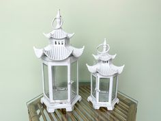 two white lanterns sitting on top of a wooden table