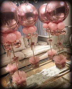 some pink balloons are on sticks in front of a couch