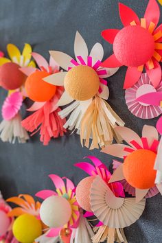 colorful paper flowers are arranged on a gray background with orange, pink, and yellow accents