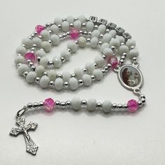 This beautiful and delicate personalized First Communion rosary for a girl or boy is a beautiful and meaningful gift for that special day of First Communion. This handmade religious jewelry is made with a beautiful Italian medal and the name of the boy or girl who will receive it and will be a permanent memory of that special day. It is a lasting reminder of God's love and blessing, as well as a special gift from godmother, aunt or grandmother to celebrate this important milestone and a reminder of faith that can be used daily. The perfect gift to express your love and faith! PRODUCT DETAILS: The Delicate Rosary is made with white glass, and with details in blue or pink depending on the case and silver details, as well as the name of the boy or girl who will receive it, made entirely by ha Adjustable Miraculous Medal For Gift, Personalized Silver Rosary For First Communion, Personalized Silver Rosary For Confirmation, Mother's Day Spiritual Rosary, Spiritual Silver Rosary As Gift, White Miraculous Medal Spiritual Jewelry, White Spiritual Cross Jewelry And Charms, White Necklace With Miraculous Medal And Round Beads, Adjustable Spiritual Rosary As Gift