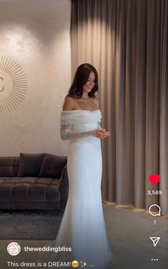 a woman in a white dress standing next to a couch