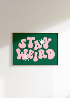 a green and pink sign that says stay weird on the side of a white wall