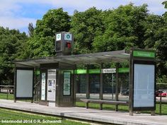 an empty bus stop sitting on the side of a road in front of trees and grass