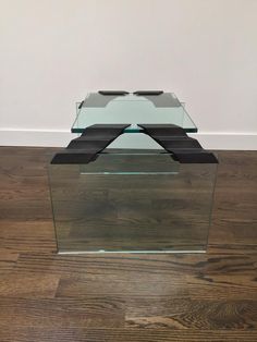 a glass coffee table with black metal legs on wood flooring in front of a white wall