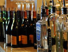 several bottles of alcohol are lined up on the bar top, and there is no image here to provide a caption for