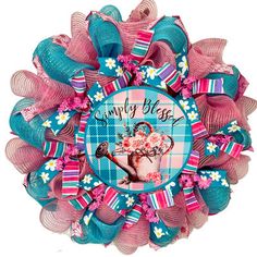 a pink, blue and white wreath with an image of a watering can on it