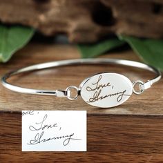 a close up of a bracelet on a wooden surface with a note attached to it