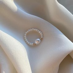 Delicate elastic fresh water pearl ring with 14kt gold filled beads. Carefully selected and high quality lustrous pearls make the ring truly beautiful and one of a kind. The delicate and minimalist design of the ring goes well with both casual and sophisticated looks. Size of the small pearl beads is approx. 2-2.5mm Size of the center large bead: 6x8mm Size of the gold filled bead: 2.5mm Follow us on INSTAGRAM: @soellejewelry Tag us on social media: #soellejewelry Packed with care and ready to s Pearl Ring Handmade, Diy Beads Ring Ideas, Pearl Beaded Ring, Ring Ideas Diy Bead, Ring Designs Beads, Silver Ring With Pearl, Baroque Pearl Ring With Pearl Drop For Weddings, White Pearl Ring With Pearl Chain, Wedding Pearl Drop Ring With Baroque Pearl