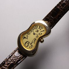 "1990s Salvador Dali museum softwatch Arabic Markers 💛Champagne  dial / Gold case 🤍Clear crystal 🖤Arabic numerals 🤍Stainless stell back 💛Original melting buckle 🤎Original leather strap used Authentic from salvador dali museum Pre-Owned Some scratch but in Very good conditions Dimension Case 🔽 High 38mm x width 24 mm Conditions 80% (The strap was used and the old one has been collected Rugged operation is not guaranteed) Because it is a watch that is almost thirty years old have some minor scratches on case (can polished) but still in working condition ✅This listed come only watch with melting buckle and strap✅ Please decide from the picture. Sold as is Some people ask questions about the product after they have made a successful purchase.  But be sure to ask \"before buying\" if you Old Watches Vintage, Salvador Dali Watch, Dali Jewelry, Dali Watch, Aesthetic Watch, Salvador Dali Museum, Dali Museum, Watch Old, Accessory Inspo