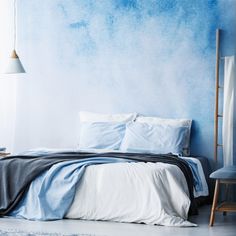 a bedroom with blue walls and white bedding