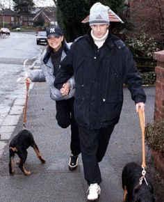 a man and woman walking their dogs down the street