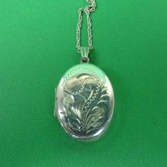 Description : A pretty hallmarked sterling silver oval locket with stylised engraved decoration together with its silver chain. Marks : Hallmarked silver for Birmingham 1992.  Maker's marks ZJ. Weight : It weighs 6.2 grams. Size :  Locket : 2.7cm long, 2cm wide. Chain : 46.5cm long Condition : In very good condition. FREE UK POSTAGE. Vintage Locket Necklace With Polished Finish For Anniversary, Engraved Oval Locket Necklace For Anniversary, Oval Engraved White Gold Necklaces, Engraved Oval White Gold Necklace, White Gold Oval Engraved Necklace, Engraved Oval White Gold Necklaces, White Gold Oval Engraved Necklaces, Engraved Silver Oval Jewelry, Classic Silver Locket Necklace With Oval Link