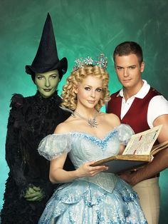 three people dressed in costumes standing next to each other and holding an open book together