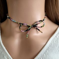 a woman wearing a multi colored beaded necklace on a mannequin's neck