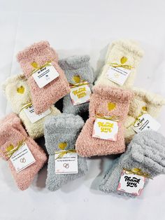 several pairs of mittens are shown on a white surface with tags attached to them