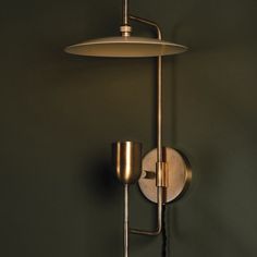 a wall mounted light with a lamp on it's side against a green wall