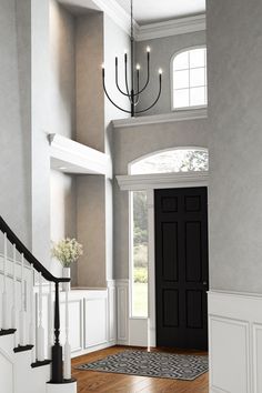 an entry way with a chandelier and black door in the center, surrounded by white trim