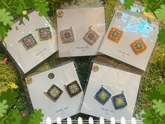 four pairs of earrings are on display in front of some green leaves and flowers,