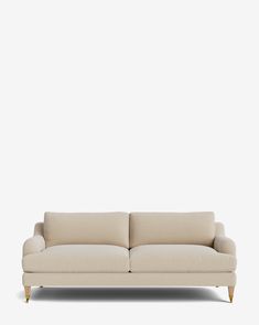 a white couch sitting on top of a wooden floor next to a wall with a light colored background