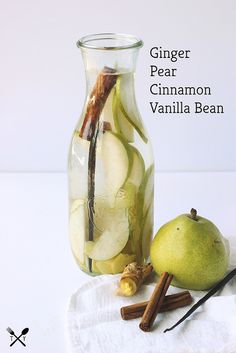 a glass bottle filled with liquid next to an apple and cinnamon