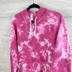 a pink and white tie dye hoodie on a hanger