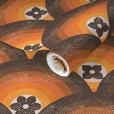 an orange and brown wallpaper with black flowers on it's sides, along with circles in the middle