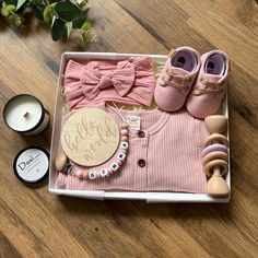 a box filled with baby items on top of a wooden floor next to candles and flowers