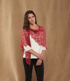 a woman standing in front of a brown backdrop wearing black pants and a red scarf