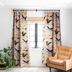 a living room filled with furniture and a large window covered in curtains next to a potted plant