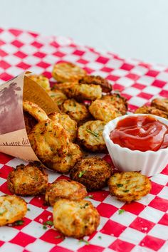 some fried food on a red and white checkered table cloth with ketchup