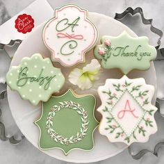 four decorated cookies on a plate with thank you written on the top and bottom letters