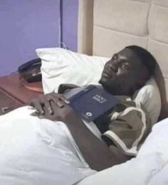 a man laying in bed with a book on his lap