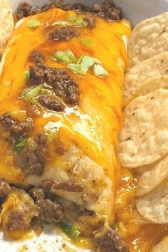 a burrito covered in cheese and ground beef surrounded by tortilla chips