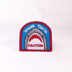 a shark tooth patch on a white background with the words shark teeth written in red and blue