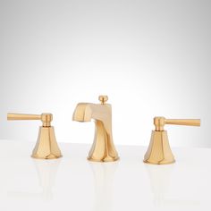 three golden faucets sitting on top of a white counter next to each other