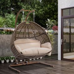 an outdoor swing chair with cushions on the back patio, next to potted plants